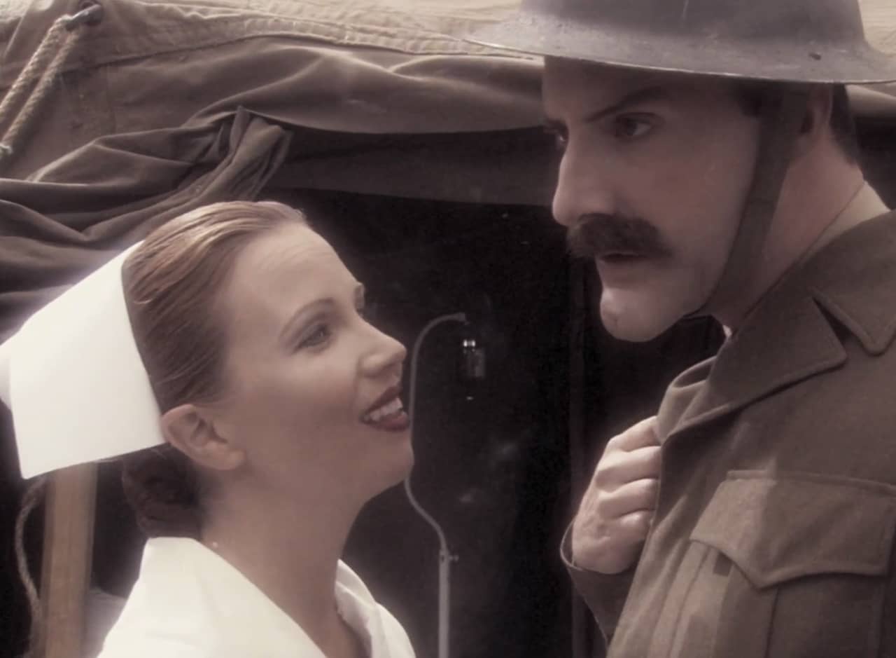 a male soldier looks into the middle distance while a female nurse looks up at him with a smile