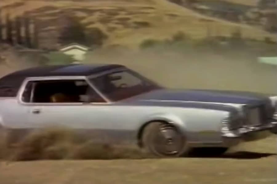 a vintage car spins out on a dirt road