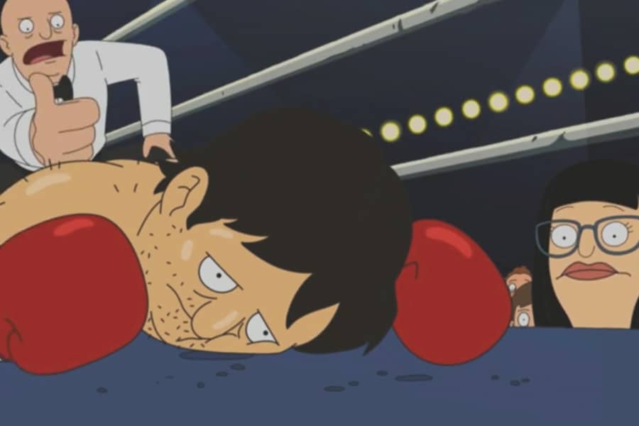 our shirtless boxer looking defeated on the floor of the ring while the referee counts and his lady friend looks concerned