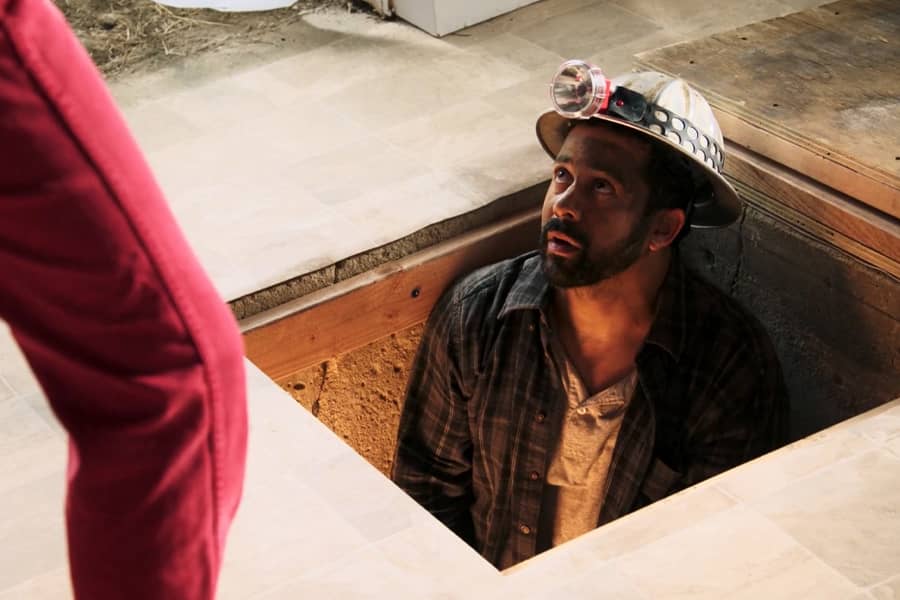 a contractor in a hard hat looks up from from a cellar door