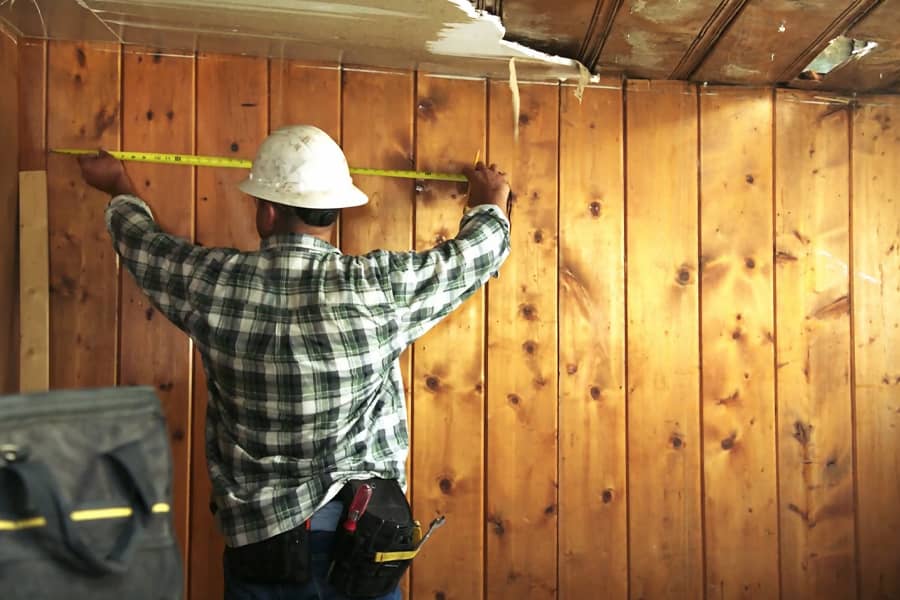 a contractor measures a wall with a measuring tape