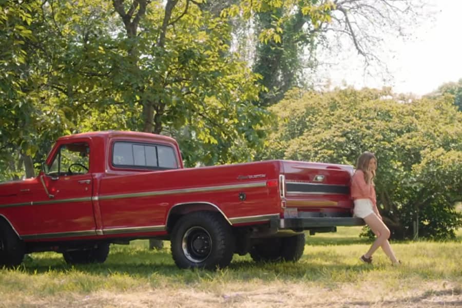 Tori sitting on the tail bumper of a pick-up truck