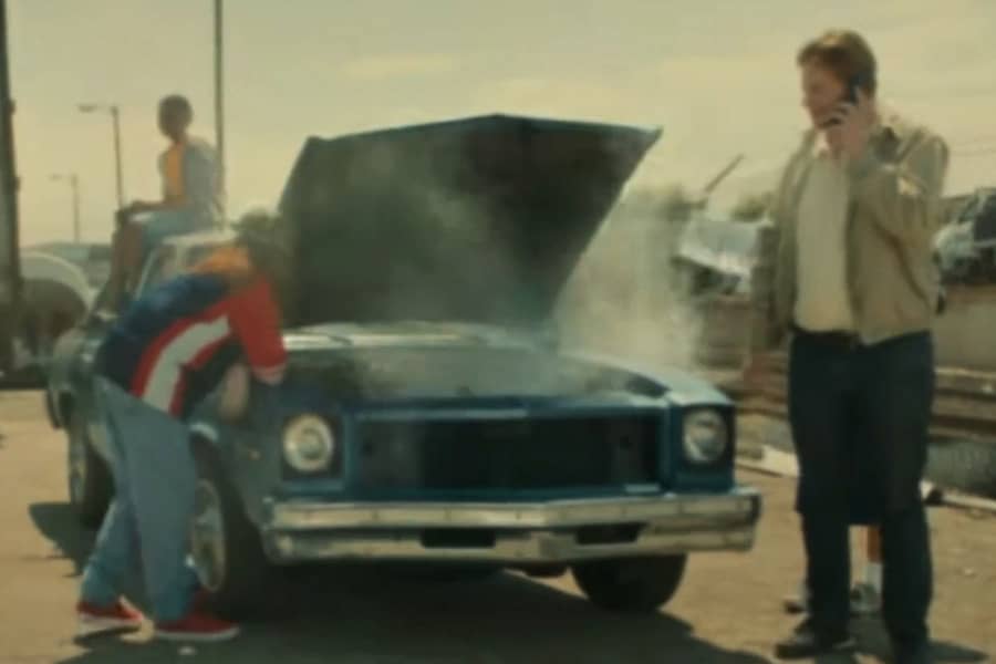 a man and some kids next to a car with smoking engine