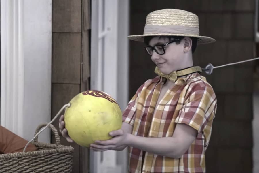 young Buster admires a tetherball while wearing a collar with a leash