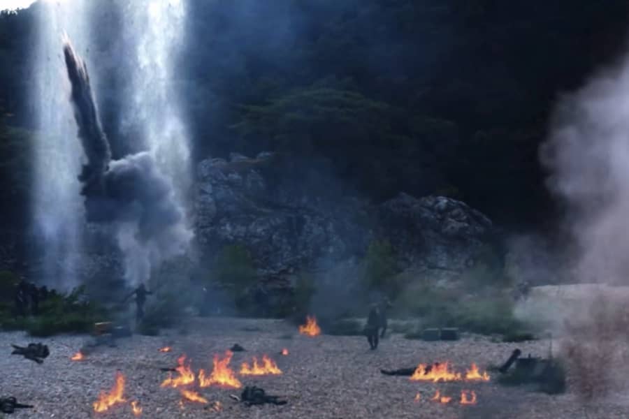 wide shot of a war zone: a pebbled valley on fire with explosions