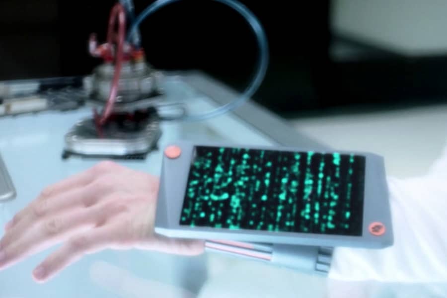 a man’s wrist is adorned with a tablet screen with green computer code