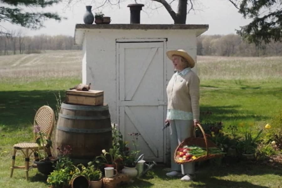 a gardening woman speaks with Otto the turtle by a garden shed