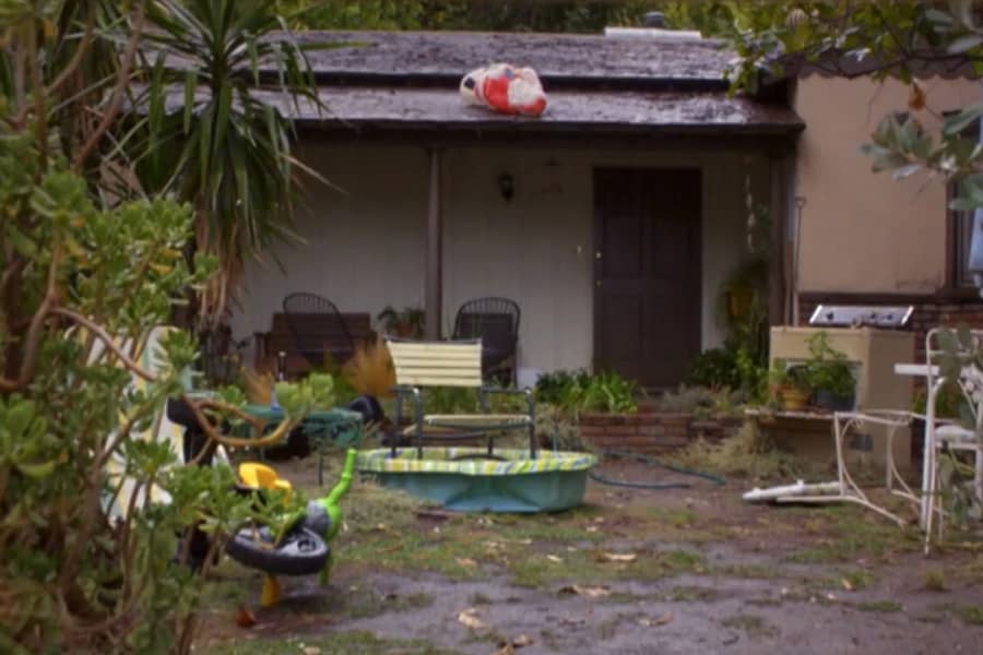 an unkempt house with junk outside and a Santa decoration on the roof