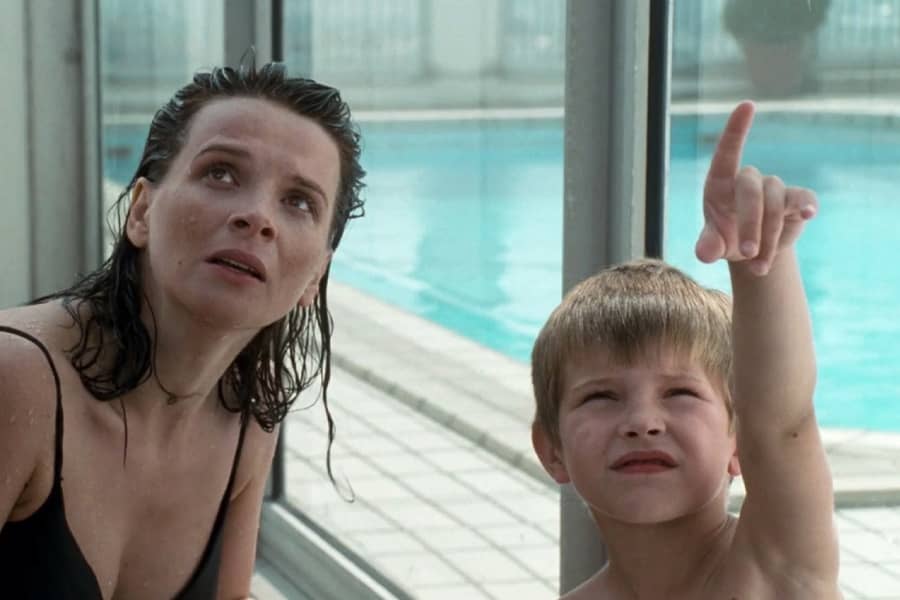 at a public pool, a young boy points in the air and Laurent looks