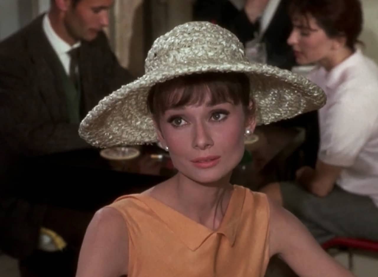 Gaby sitting at a cafe wearing a straw sun hat