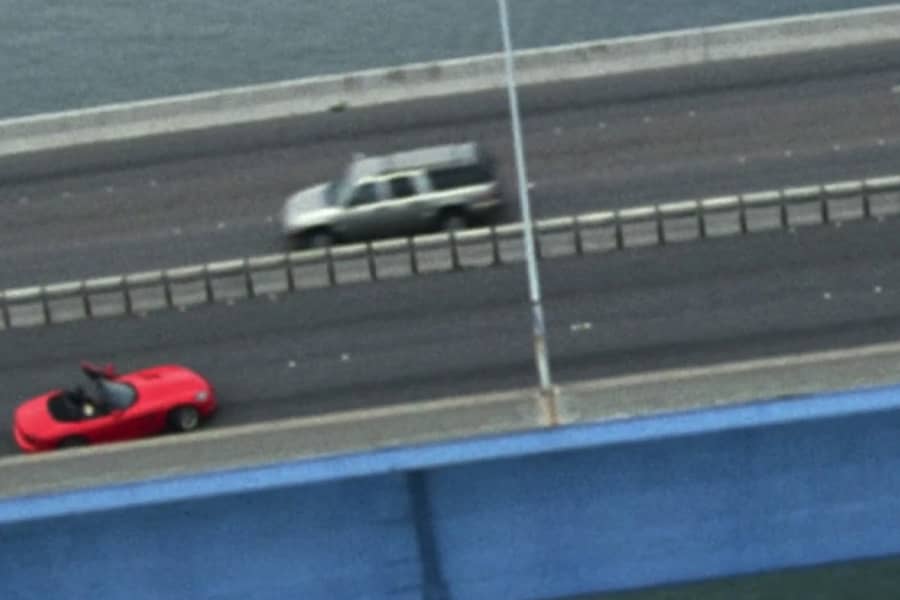 a helicopter shot of an abandoned car on a highway bridge